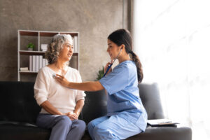 Home health care nurse checks the pulse of an elderly patient