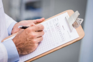 Close up of doctor hand filling medication list for a patient. Detail of hand of senior nurse complete the form of medicine. Doctor writing list of patient medicine in a hospital.