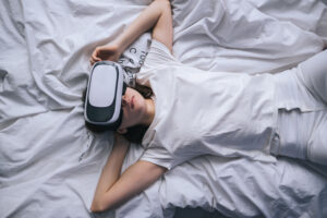Woman uses virtual reality glasses at home on the bed. Plays games, technologies of the future.